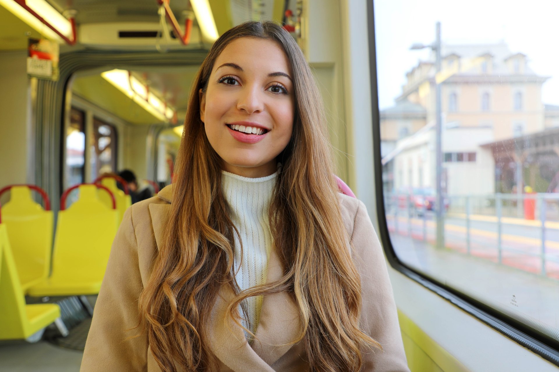 Uśmiechnięta dziewczyna w płaszczu jedzie tramwajem