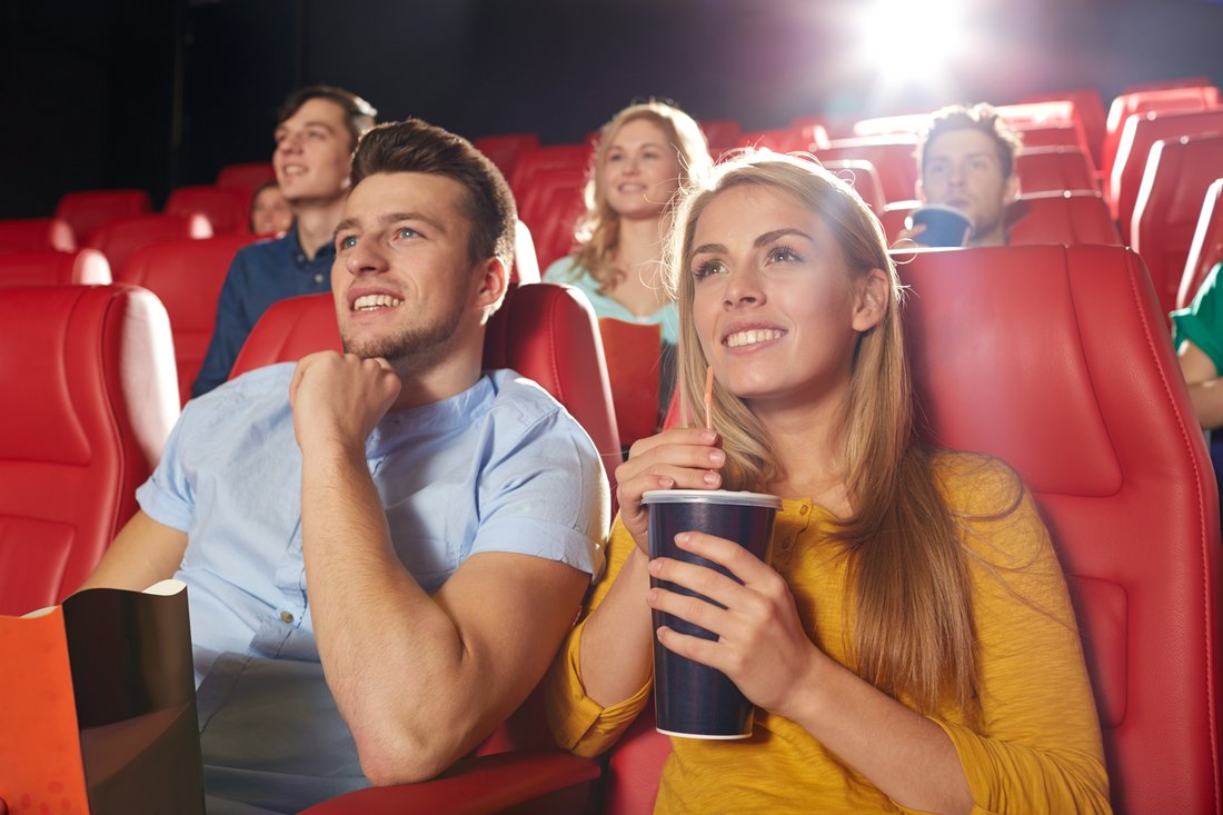 Znajomi z napojem oglądają film w kinie